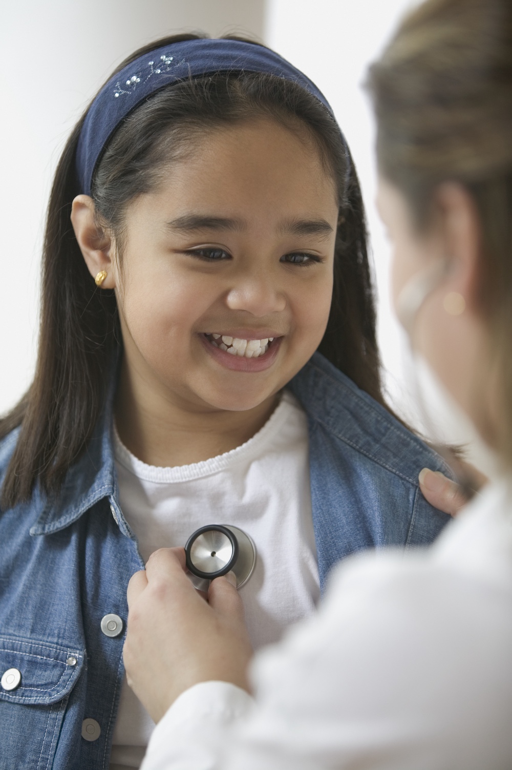 Female doctor listening to young girl's heartbeat